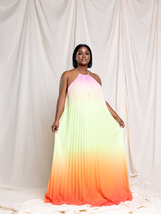 Tamie wearing the Radiant Sunset pleated maxi dress with halter neckline and ombré fading to orange at the hem, front view